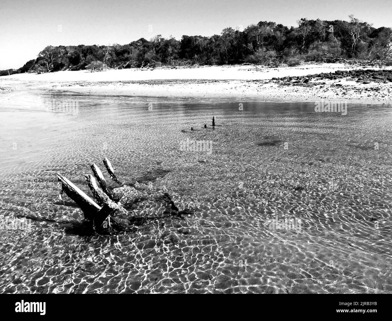 An old wreck of a dhow, which sunk in the shallow water surrounding the Inhaca Barrier Island of the coast of Mozambique in black and white. Stock Photo