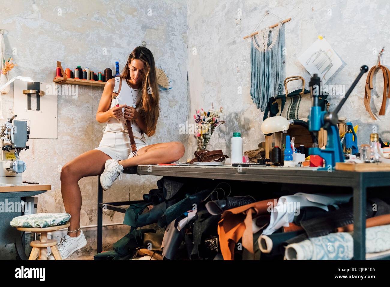 Young fashion designer making leather accessory at workshop Stock Photo