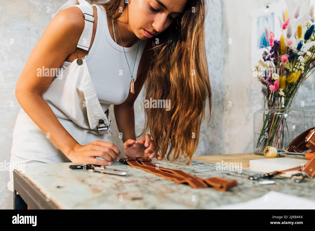 Young craftsperson making leather accessory at workshop Stock Photo
