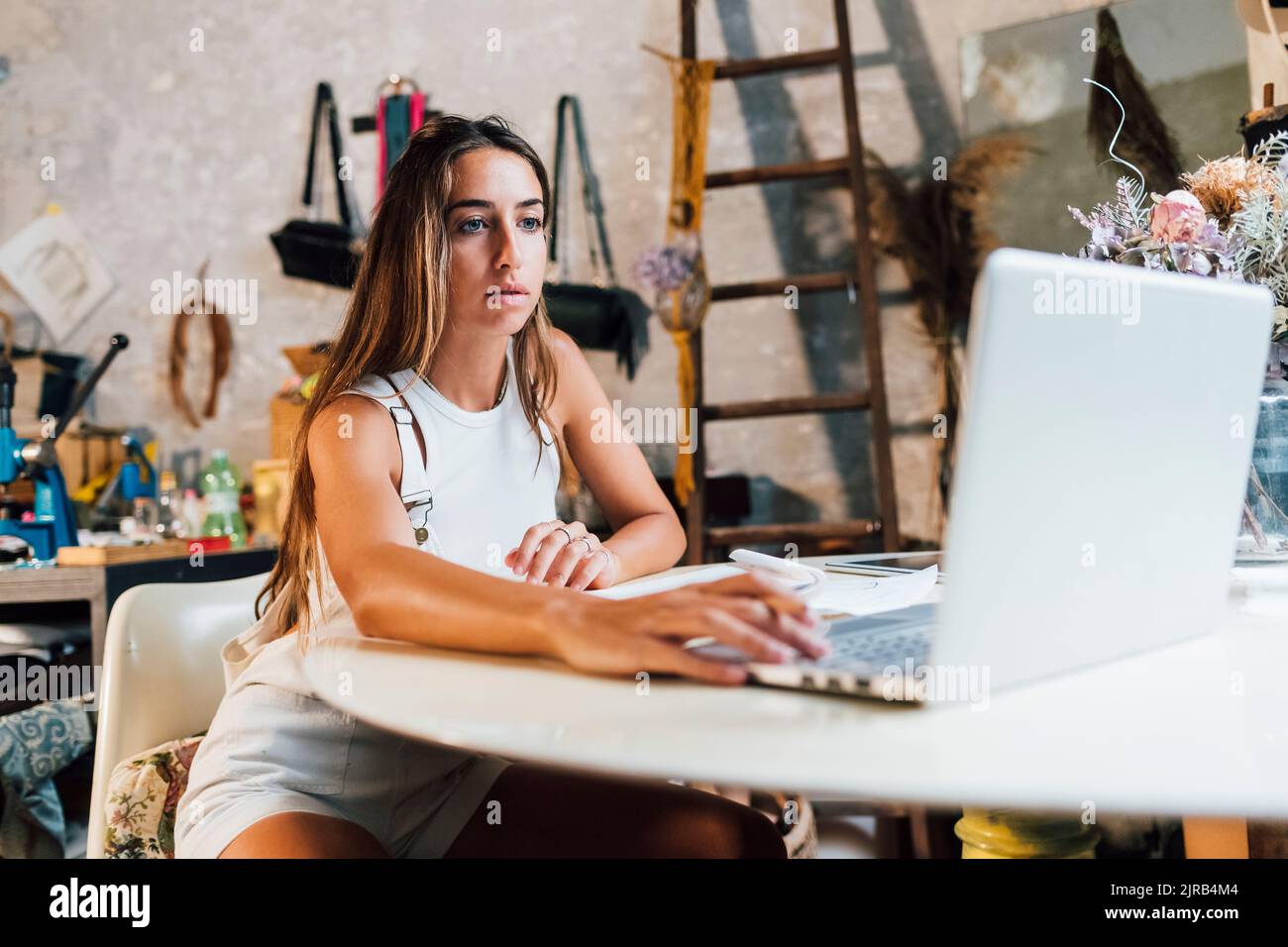 Fashion designer using laptop at desk in workshop Stock Photo