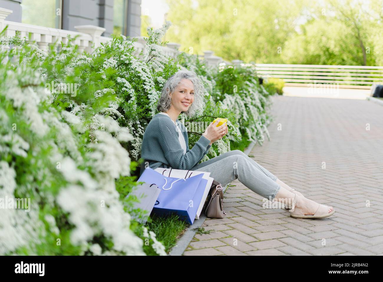 Smiling woman holding gift box sitting amidst plants Stock Photo