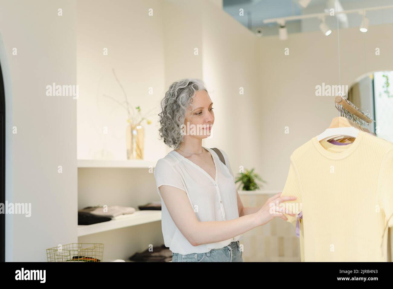 Woman choosing clothes hanging on rack at store Stock Photo