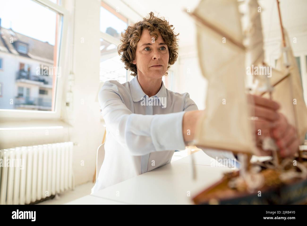 Businesswoman with ship model working in office Stock Photo