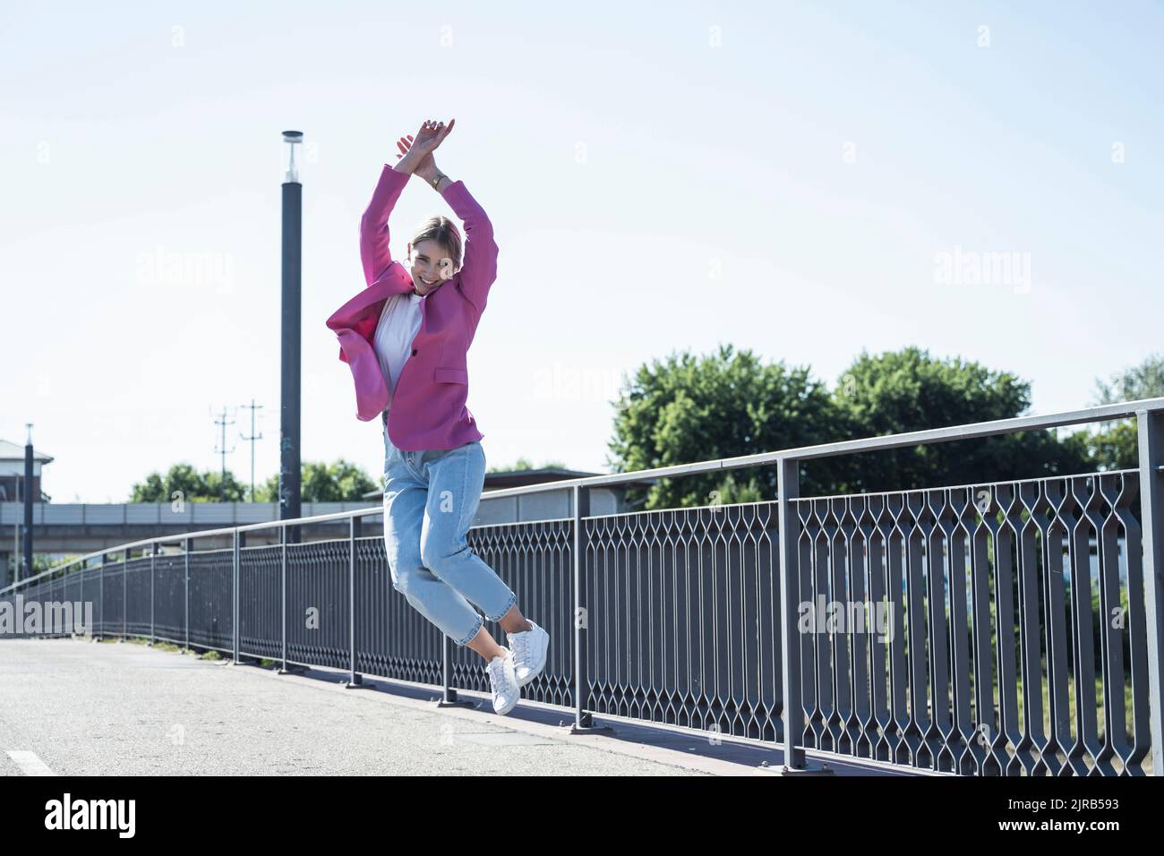 Happy young woman jumping in front of railing Stock Photo Alamy
