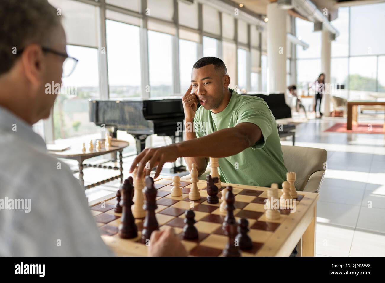 Businessman picking up chess piece playing board game with colleague in office Stock Photo