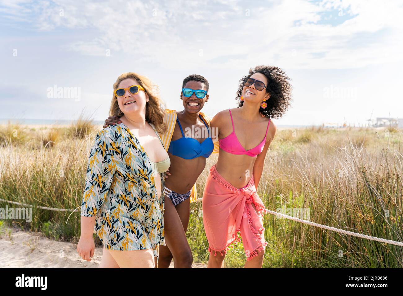 Multiracial women in bikinis at beach on sunny day Stock Photo