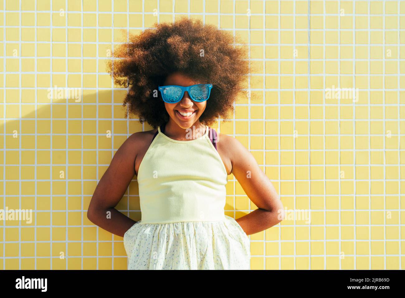 Happy girl with hands behind back wearing sunglasses Stock Photo