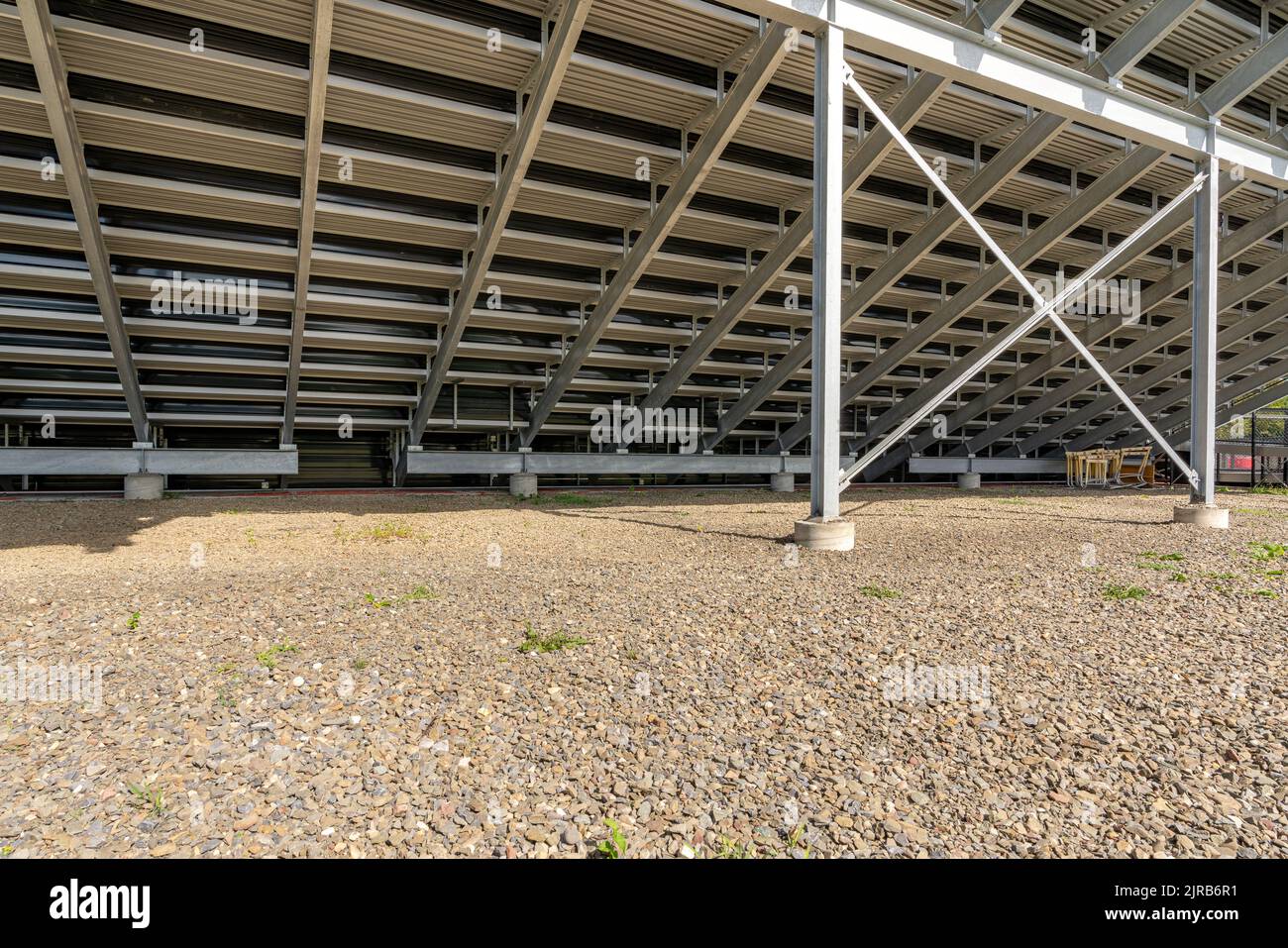 Angle view of under stadium bleachers, steal I-Beam bleachers with X cross brace, with stone surface. Stock Photo