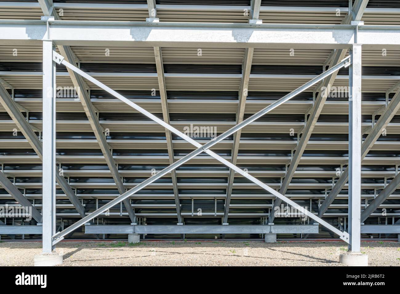 Straight on view of under stadium bleachers, steal I-Beam bleachers with X cross brace, with stone surface. Stock Photo