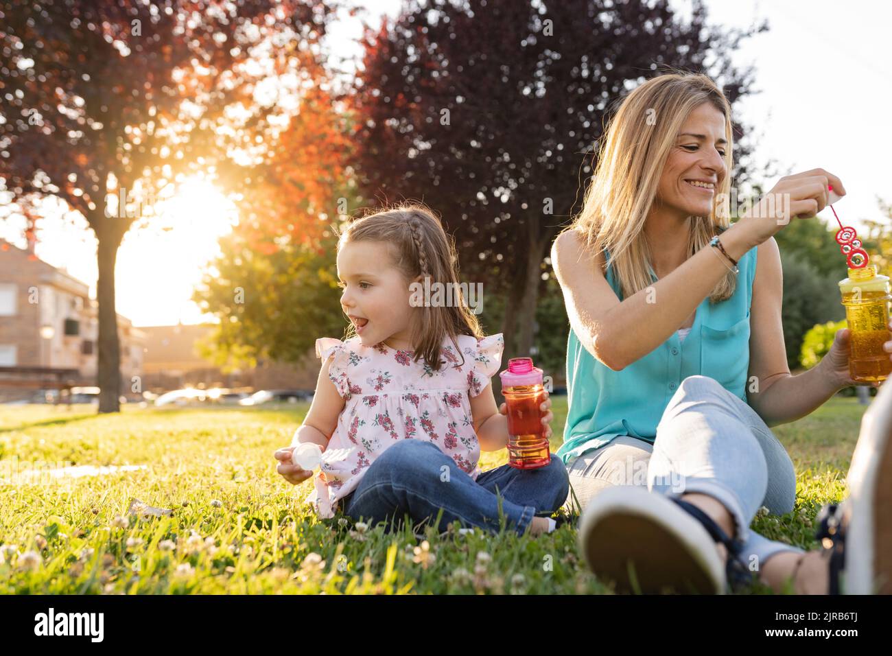 Smiling mother and daughter with bubble wands at park Stock Photo