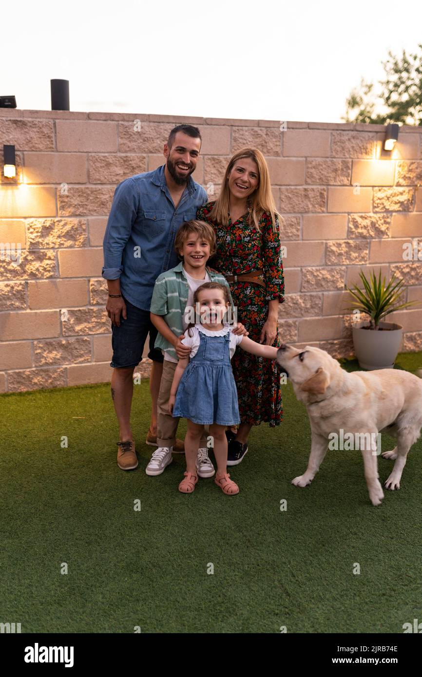 Happy family with dog standing in front of wall Stock Photo