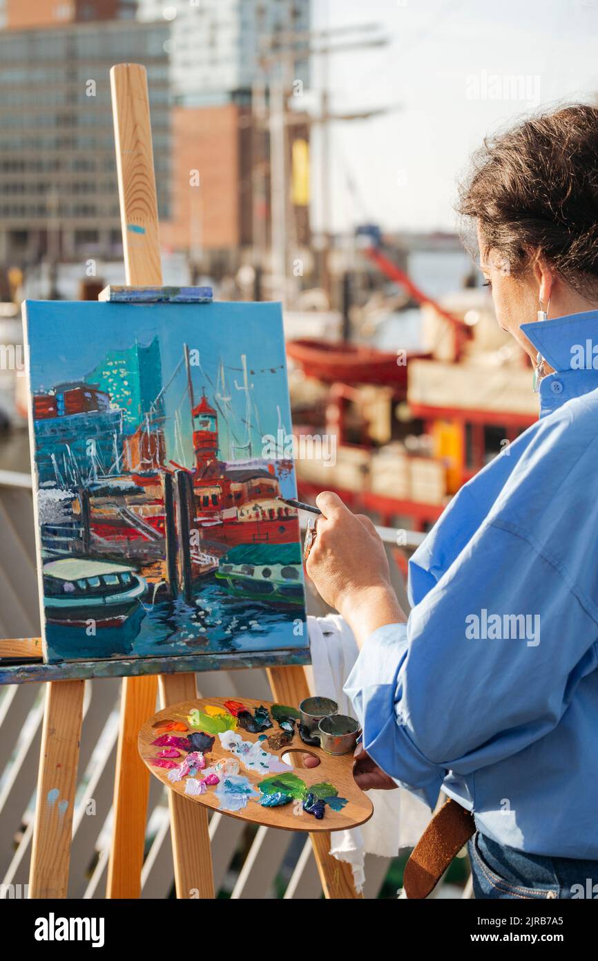 Female painter holding palette painting on canvas at harbor Stock Photo ...