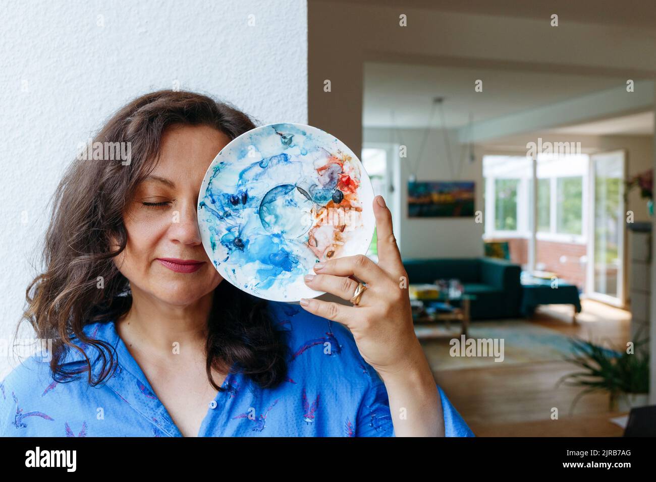 Artist covering eye with color palette at home Stock Photo