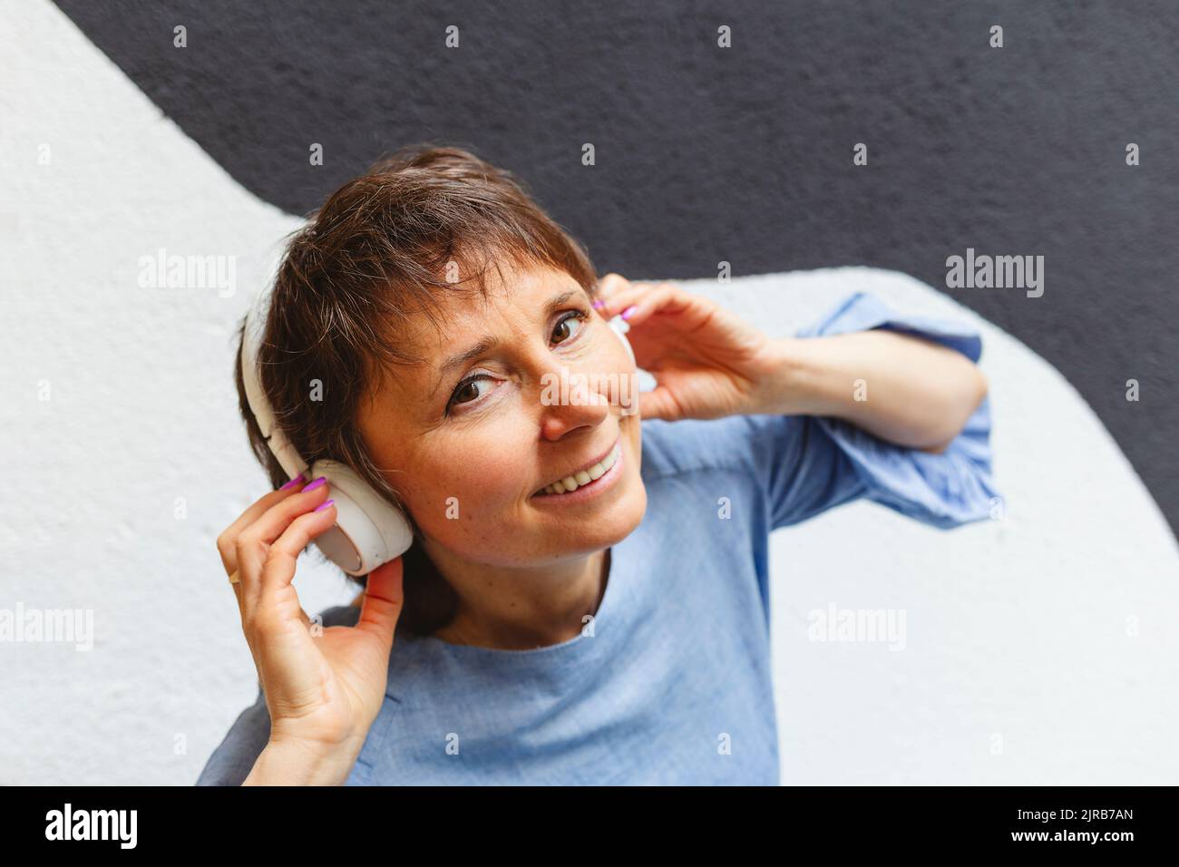 Smiling mature woman listening music with headphones Stock Photo