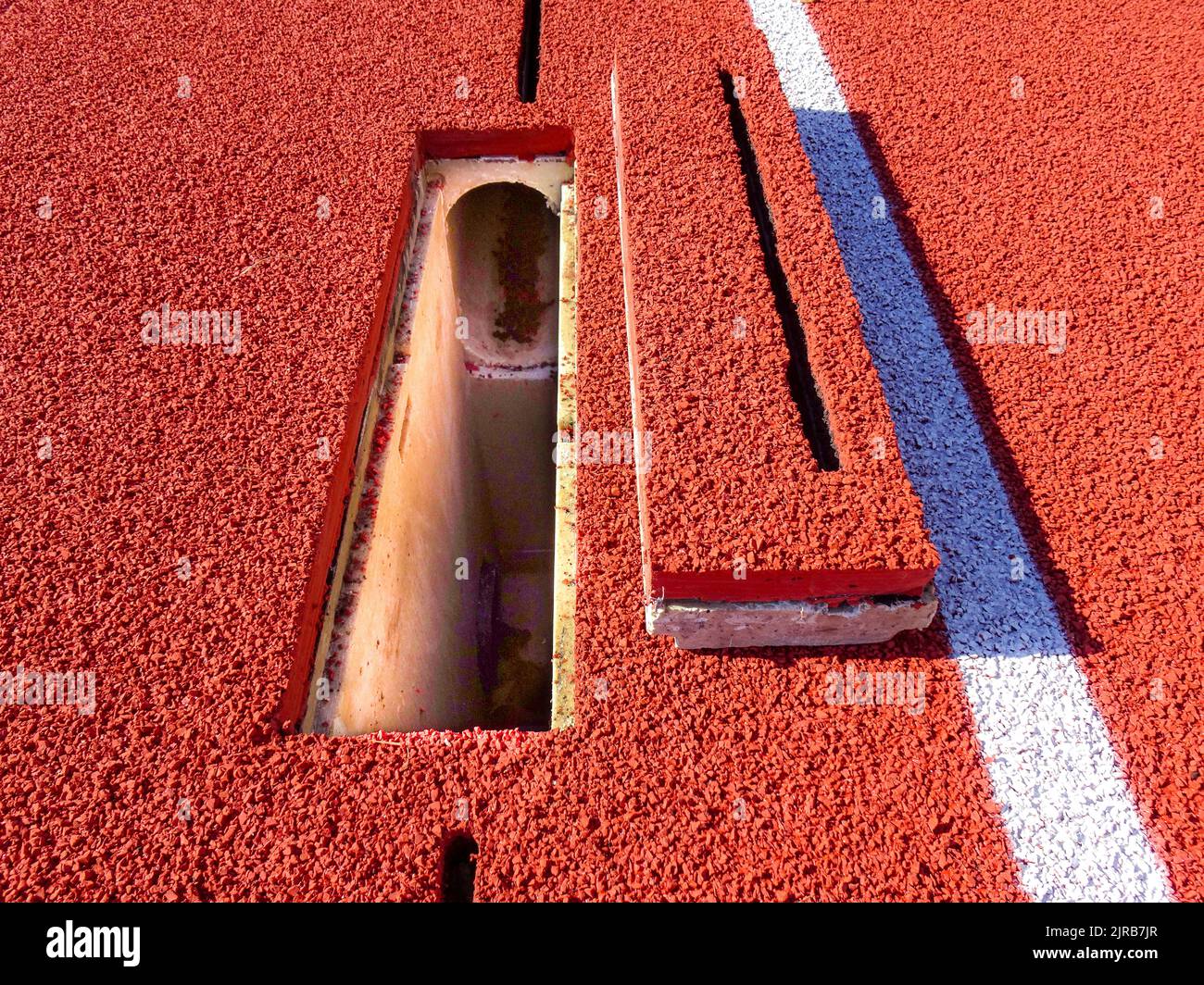 Example of a new running track with slot drain cleanout with cover removed. Stock Photo