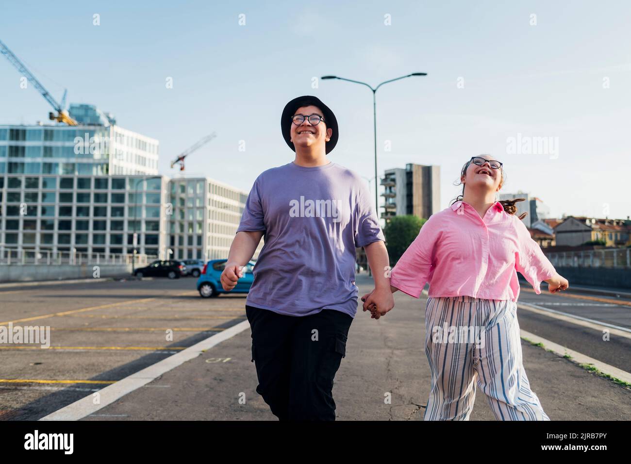 Happy brother and sister holding hands and walking on street Stock ...