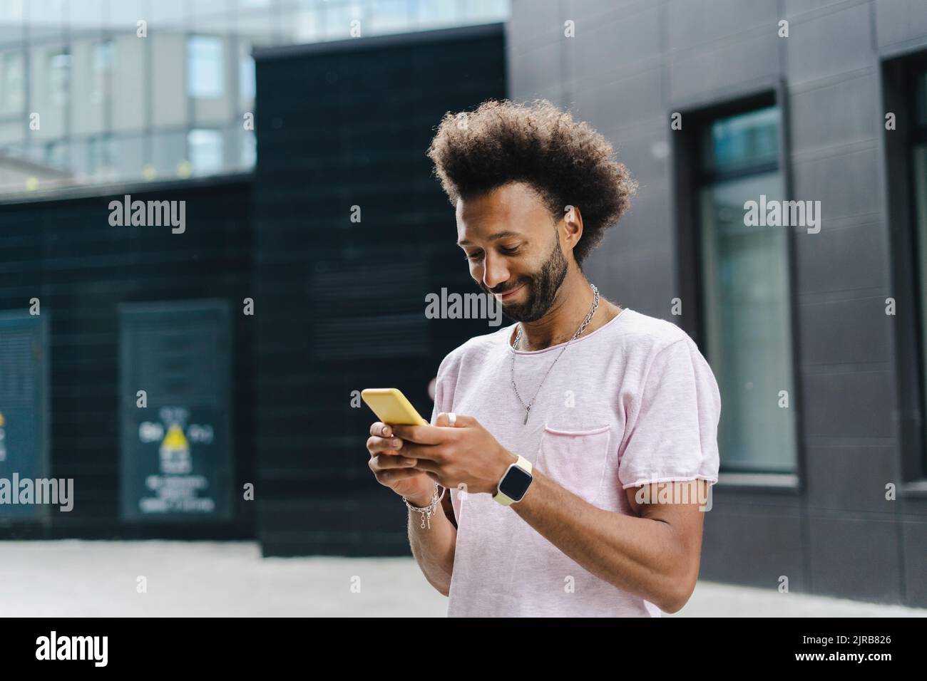 Smiling man using mobile phone near building Stock Photo