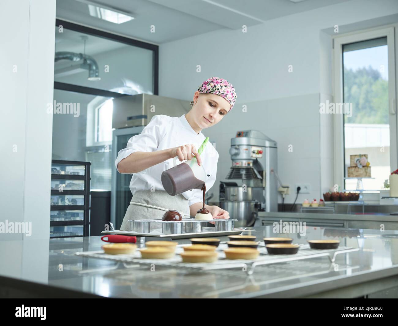 Young confectioner pouring chocolate syrup on dessert Stock Photo