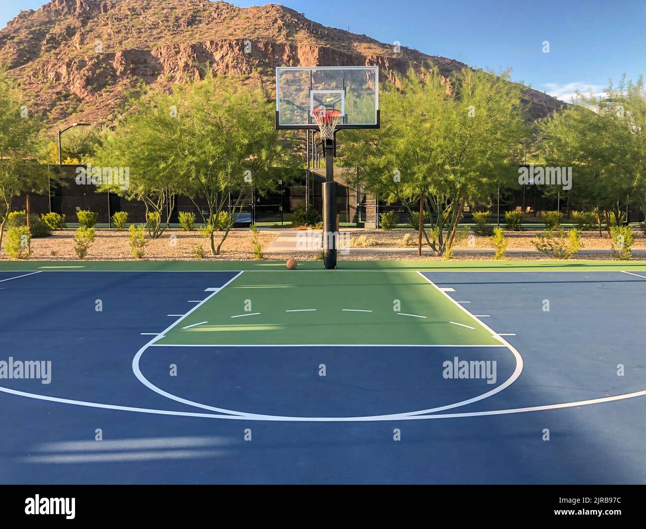 Mountain side blue and green outdoor basketball court with ball Stock