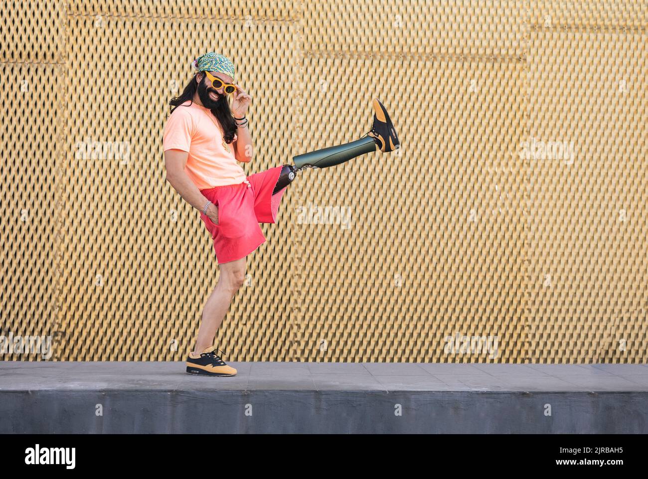 Smiling hipster man with prosthetic leg kicking in front of wall Stock Photo Alamy