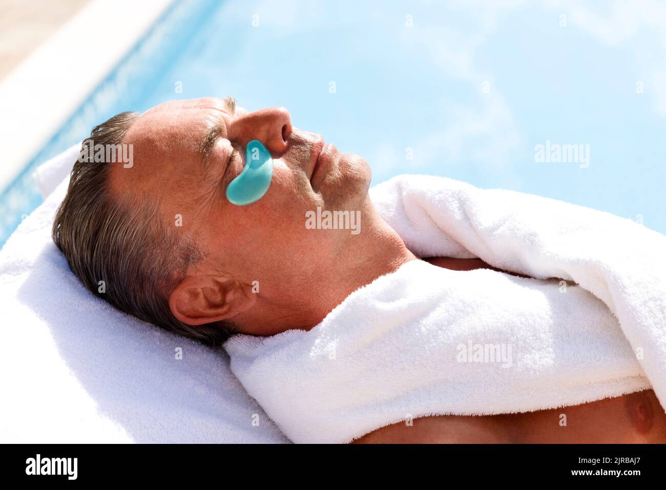 Mature man with collagen patch below eye at pool spa Stock Photo