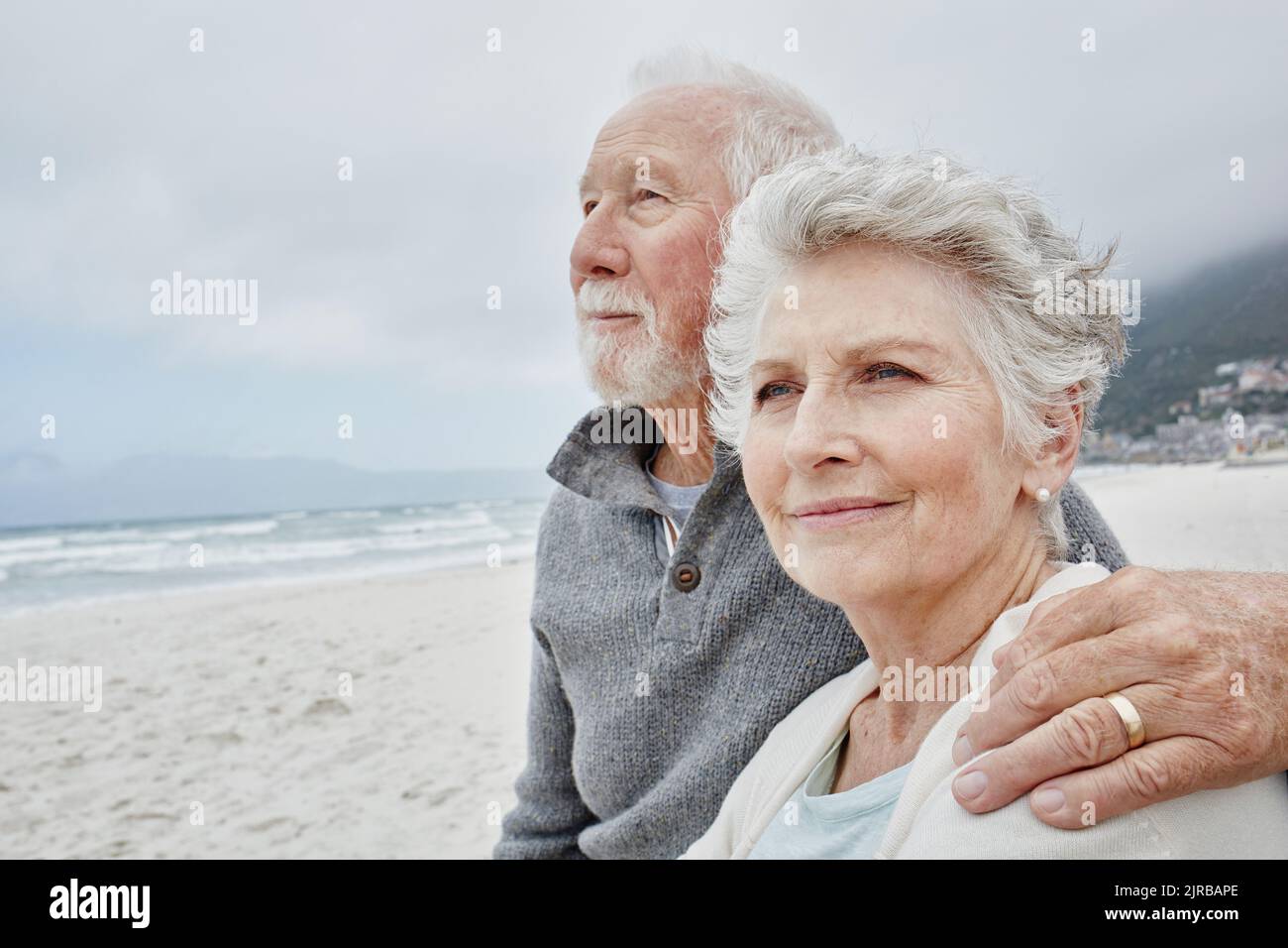 Senior couple standing on the beach with arms around Stock Photo - Alamy