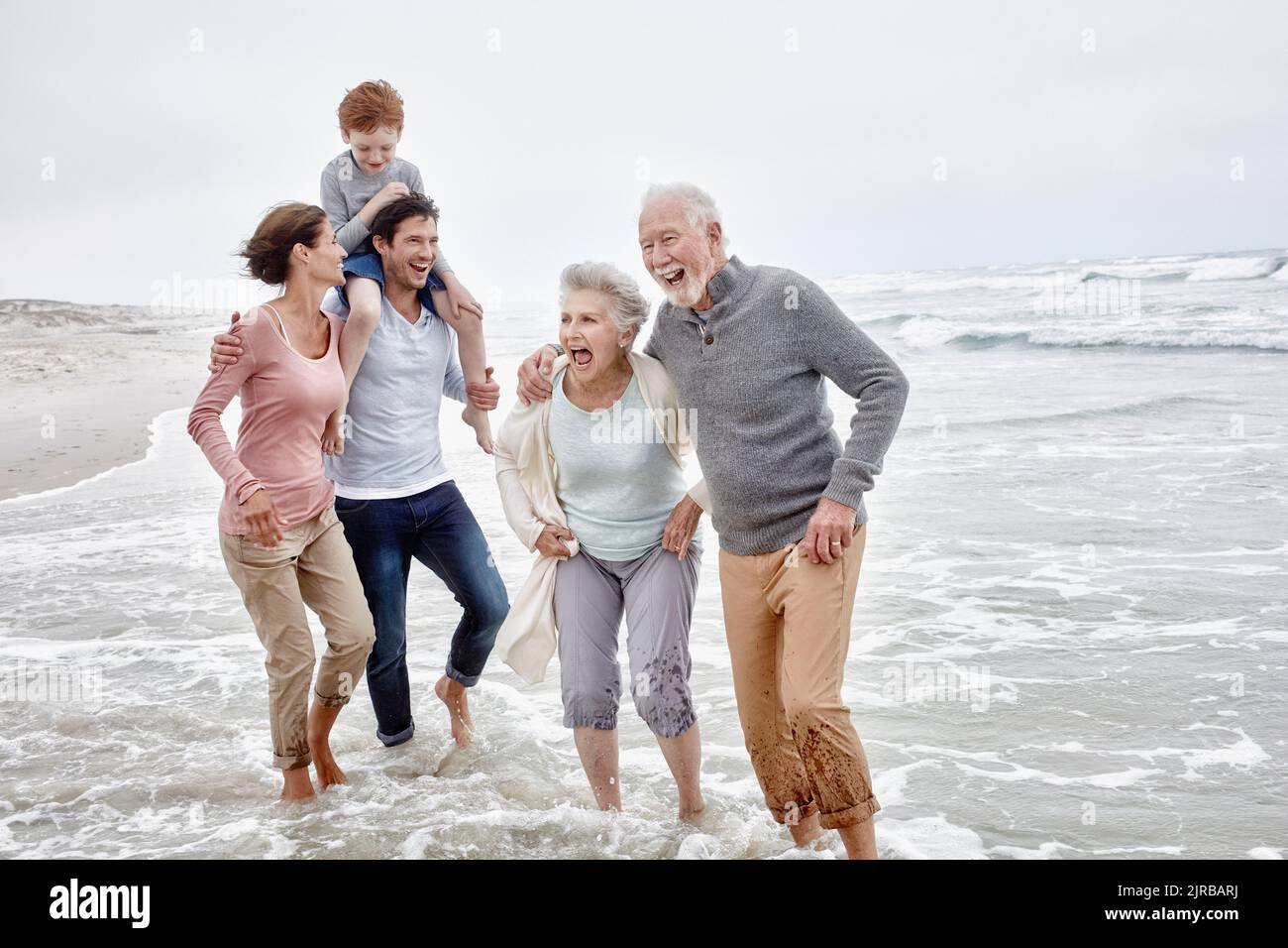 Happy couple spending quality time at the beach with son and grandparents Stock Photo
