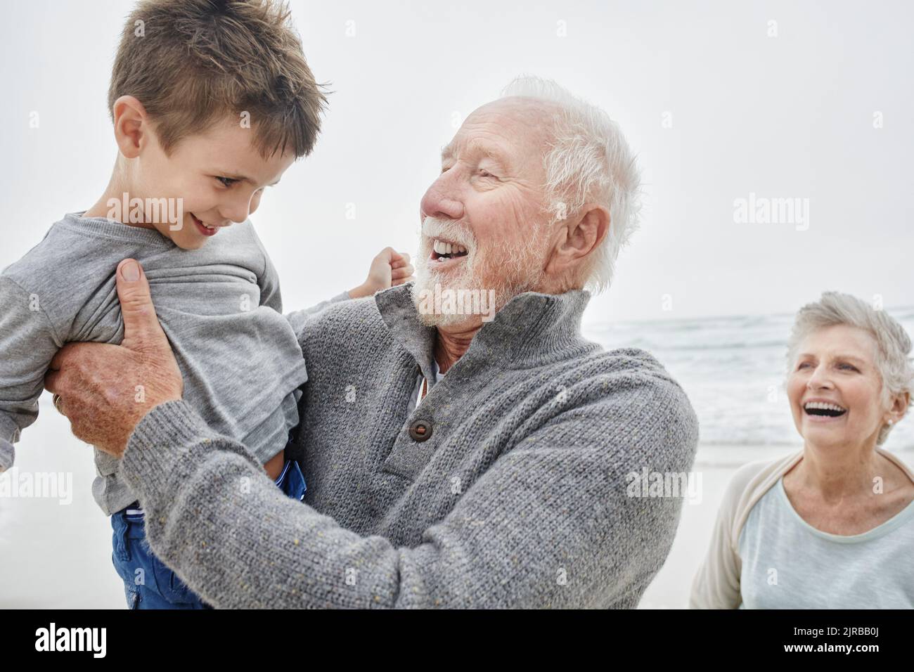 Happy grandparents spending quality time on the beach with grandson Stock Photo