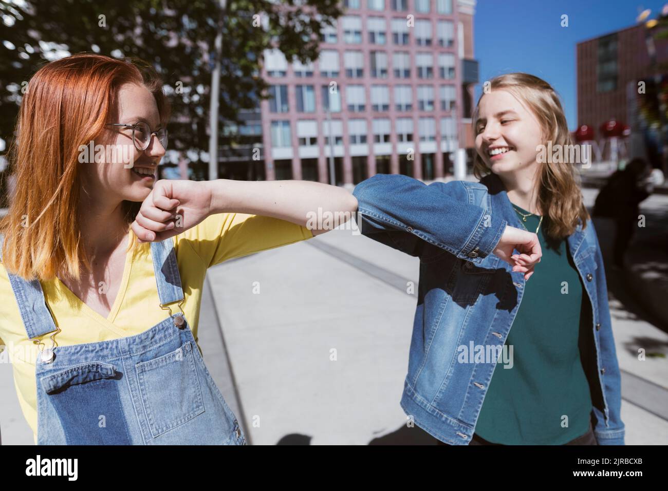 Smiling young friends doing elbow bump Stock Photo
