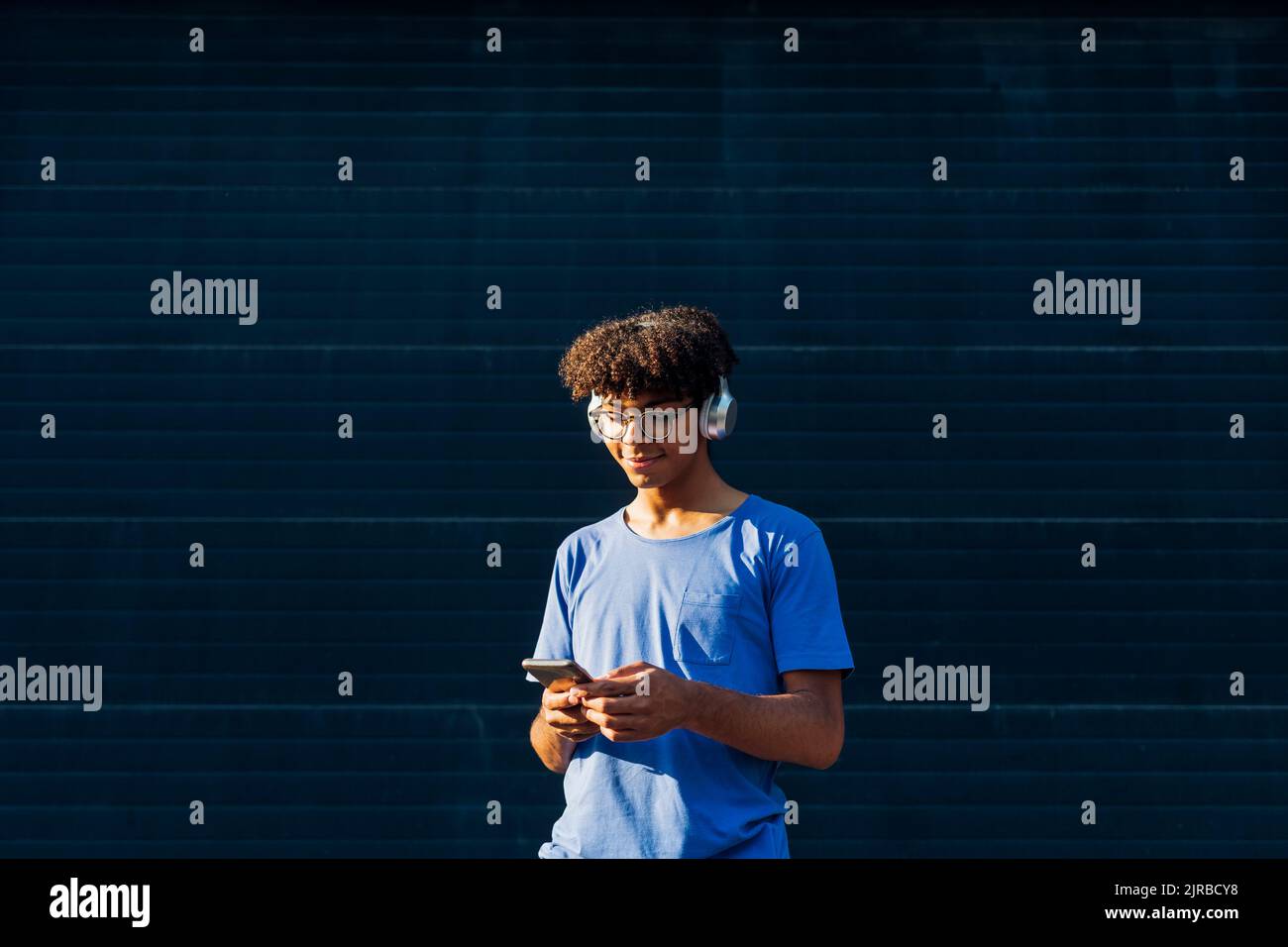 Smiling man wearing headphones using smart phone Stock Photo