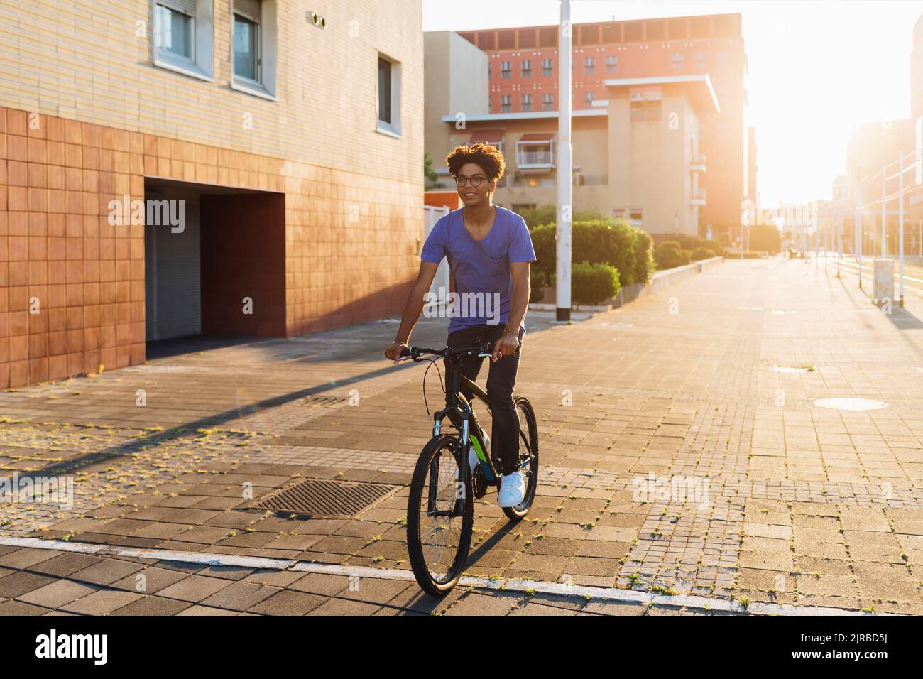 Smiling man cycling in city at sunset Stock Photo