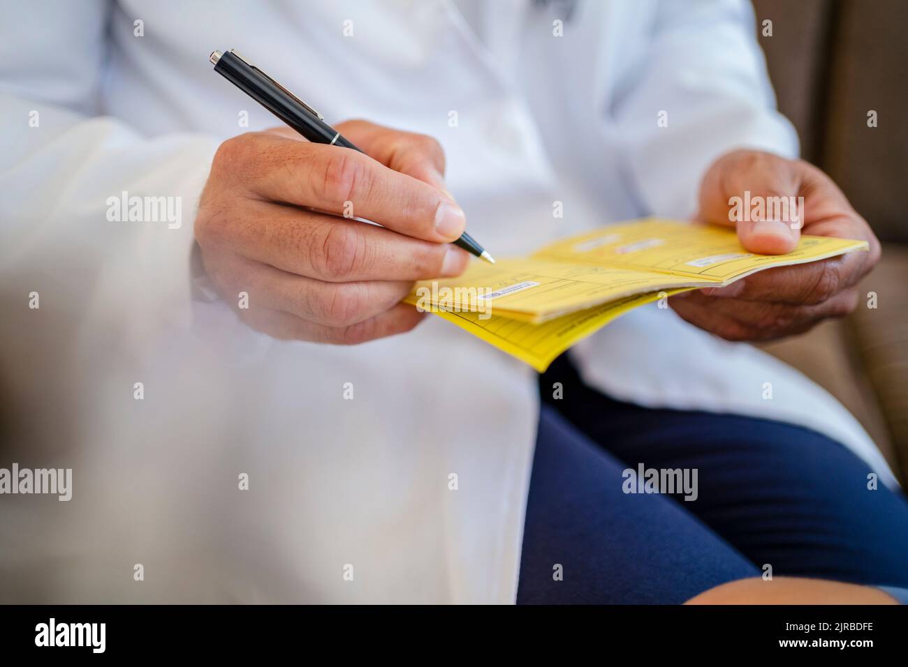 Close-up of doctor writing in vaccination pass Stock Photo