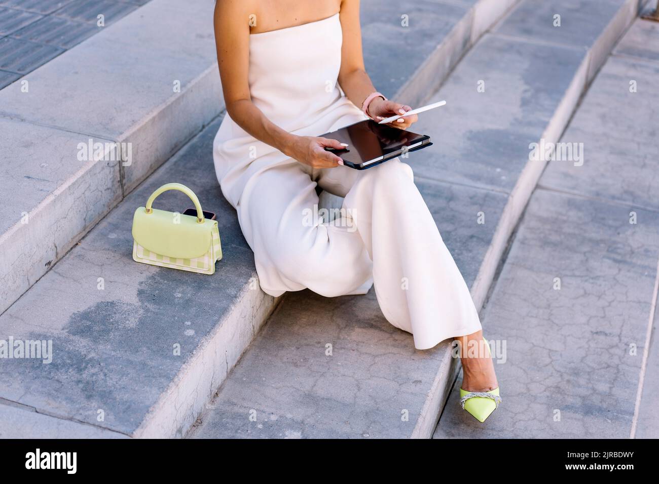 Woman using tablet PC sitting on steps Stock Photo