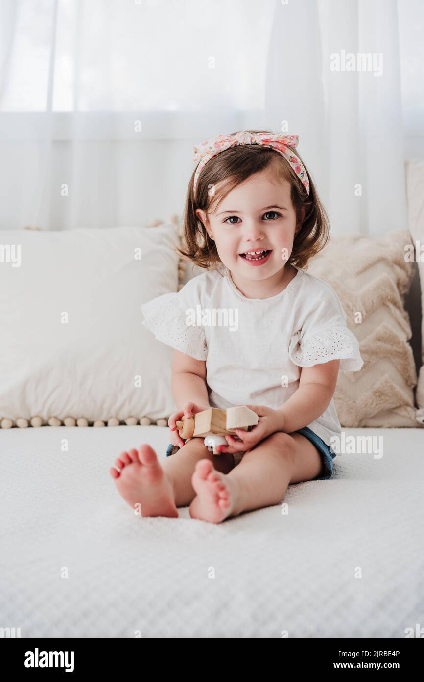 Happy cute girl sitting on sofa in living room at home Stock Photo - Alamy