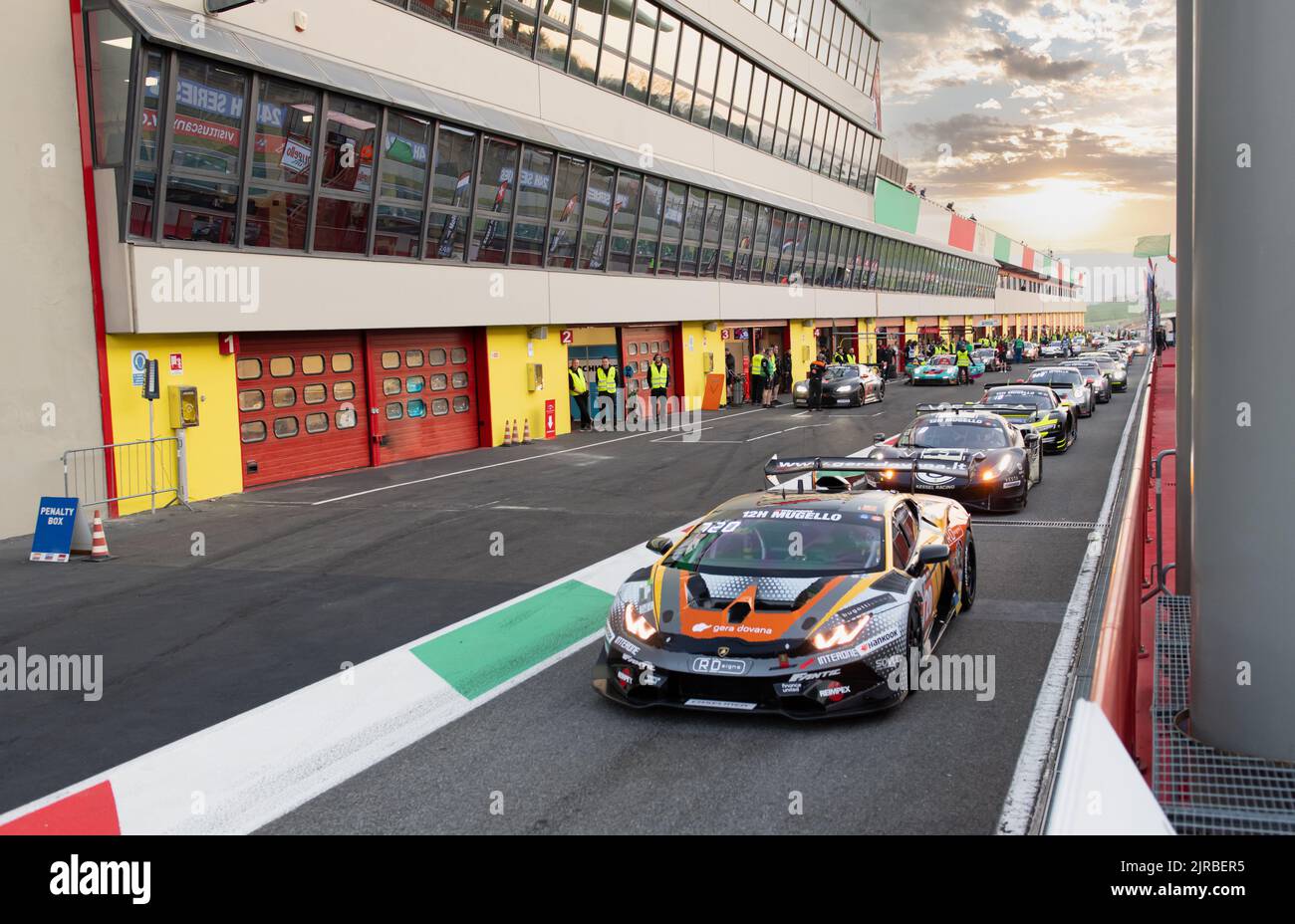Motor sport scene GT race supercars aligned in circuit pit lane at sunset. Mugello, Italy, march 25 2022. 24 Hours series Stock Photo