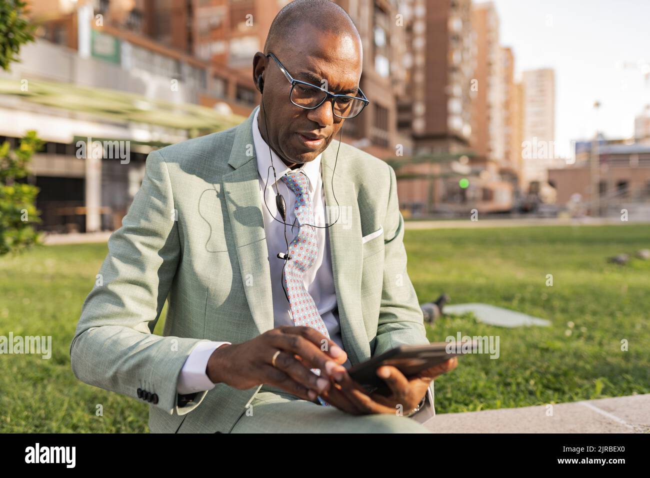 Businessman wearing In-ear headphones using tablet PC at financial district Stock Photo