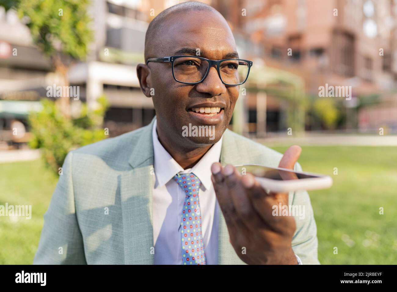 Smiling businessman talking on smart phone speaker Stock Photo