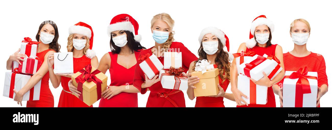 happy women in medical masks with christmas gifts Stock Photo