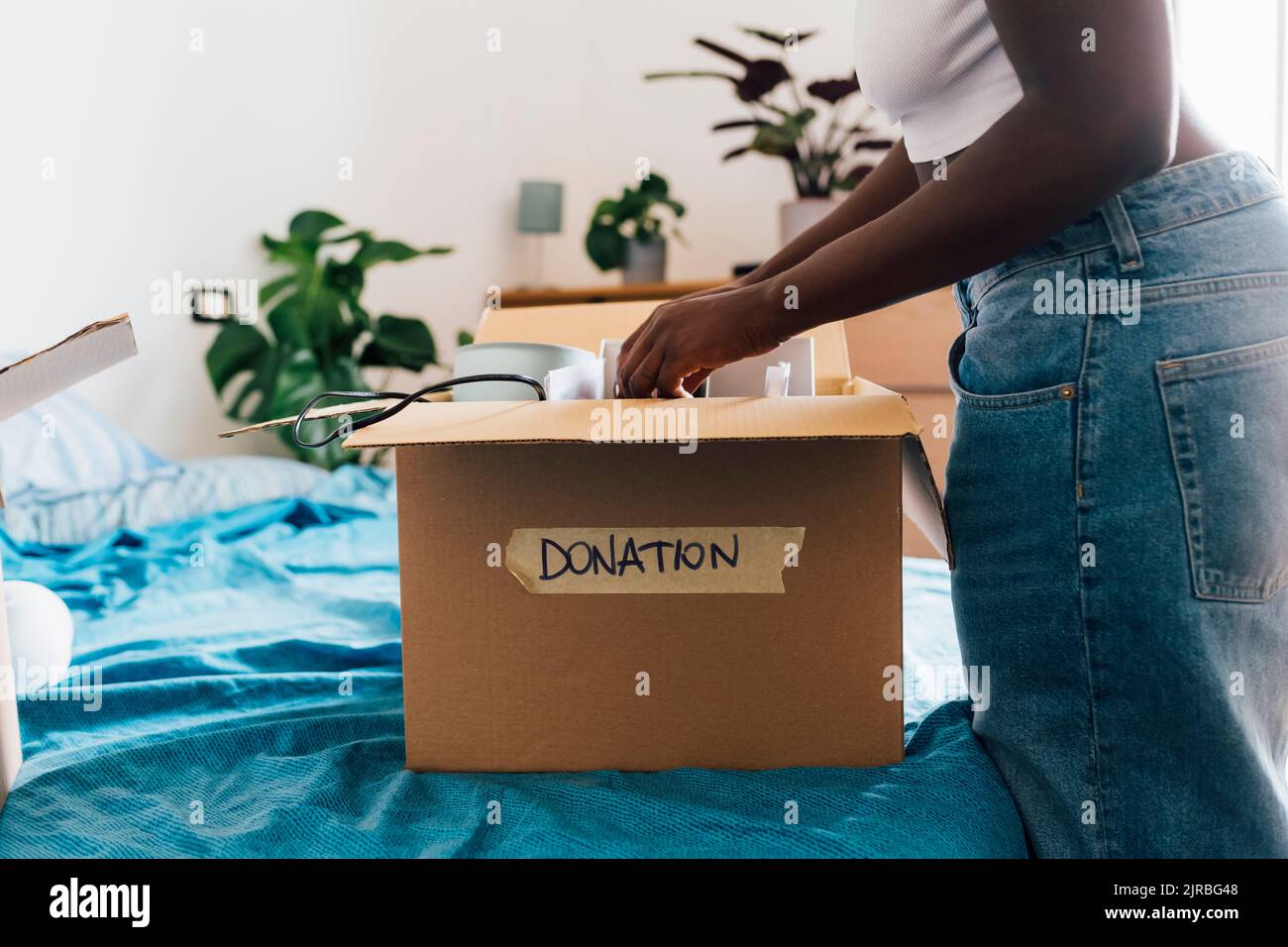 Woman packing donation box on bed at home Stock Photo Alamy