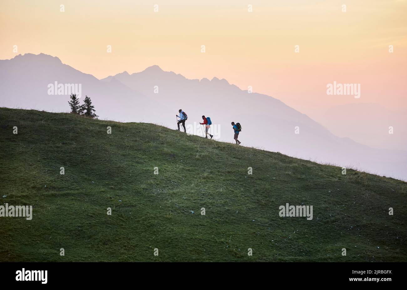 Hikers with hiking poles on mountain at sunrise, Mutters, Tyrol, Austria Stock Photo