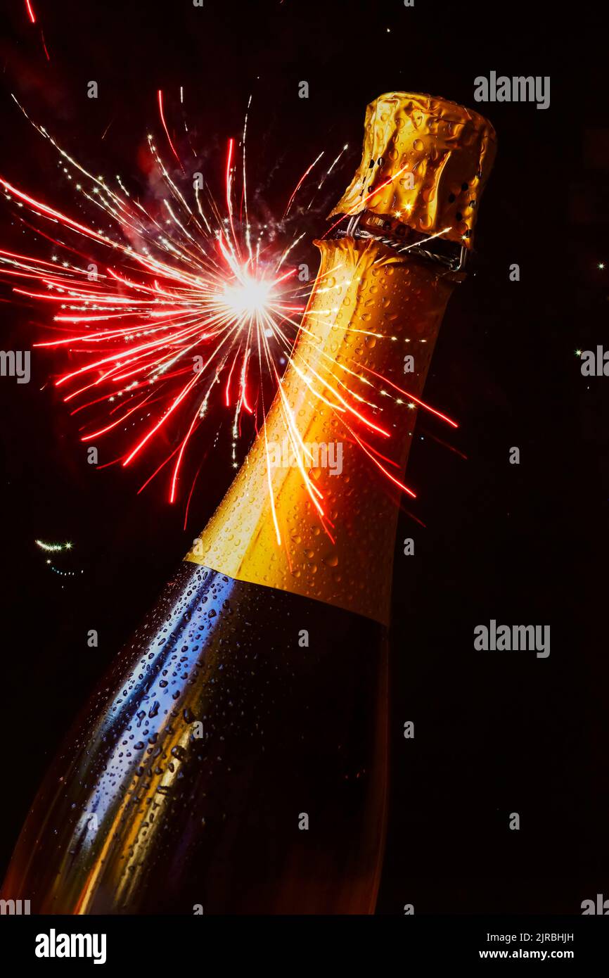 Bottle of champagne against exploding fireworks Stock Photo