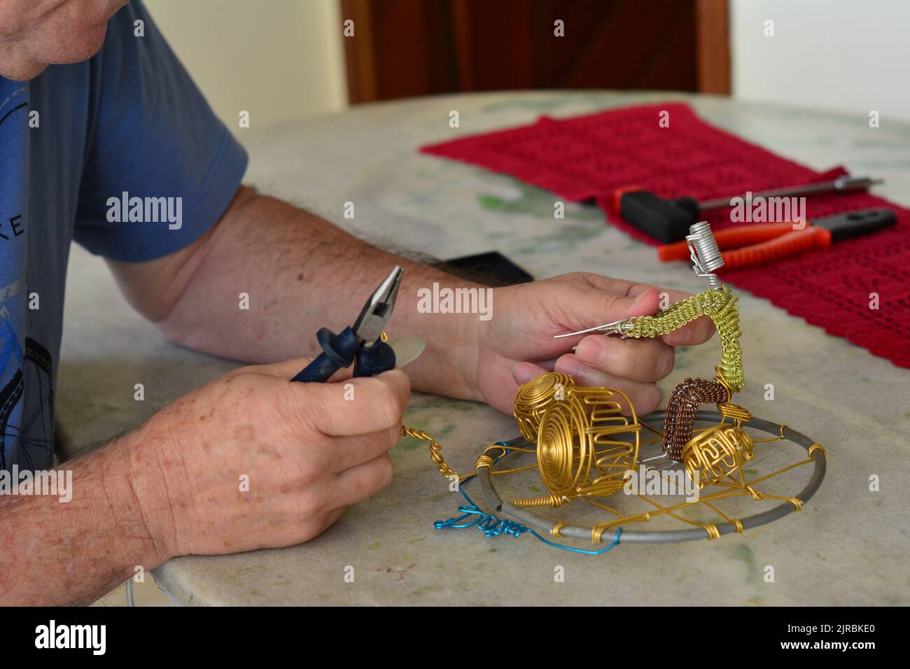 Man producing a handcraft drums with various materials, special pliers, with skillful hands on a granite table and some items, selective focus. blurr Stock Photo