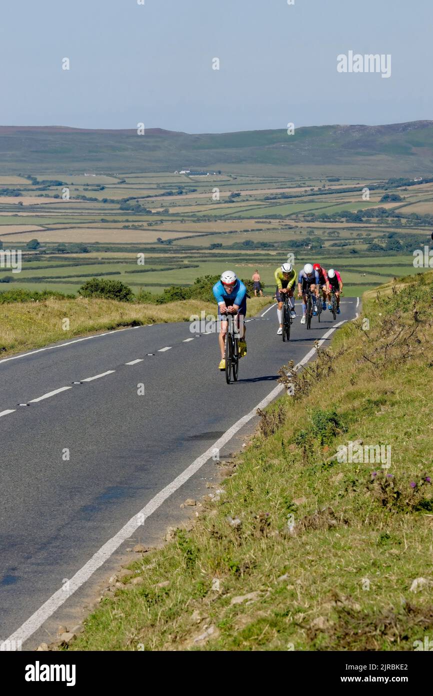 7thAug22 Gower Swansea Wales UK Triathlon Ironman cycling event Head-on view of cyclists single file on flat section at hilltop Moving towards camera. Stock Photo