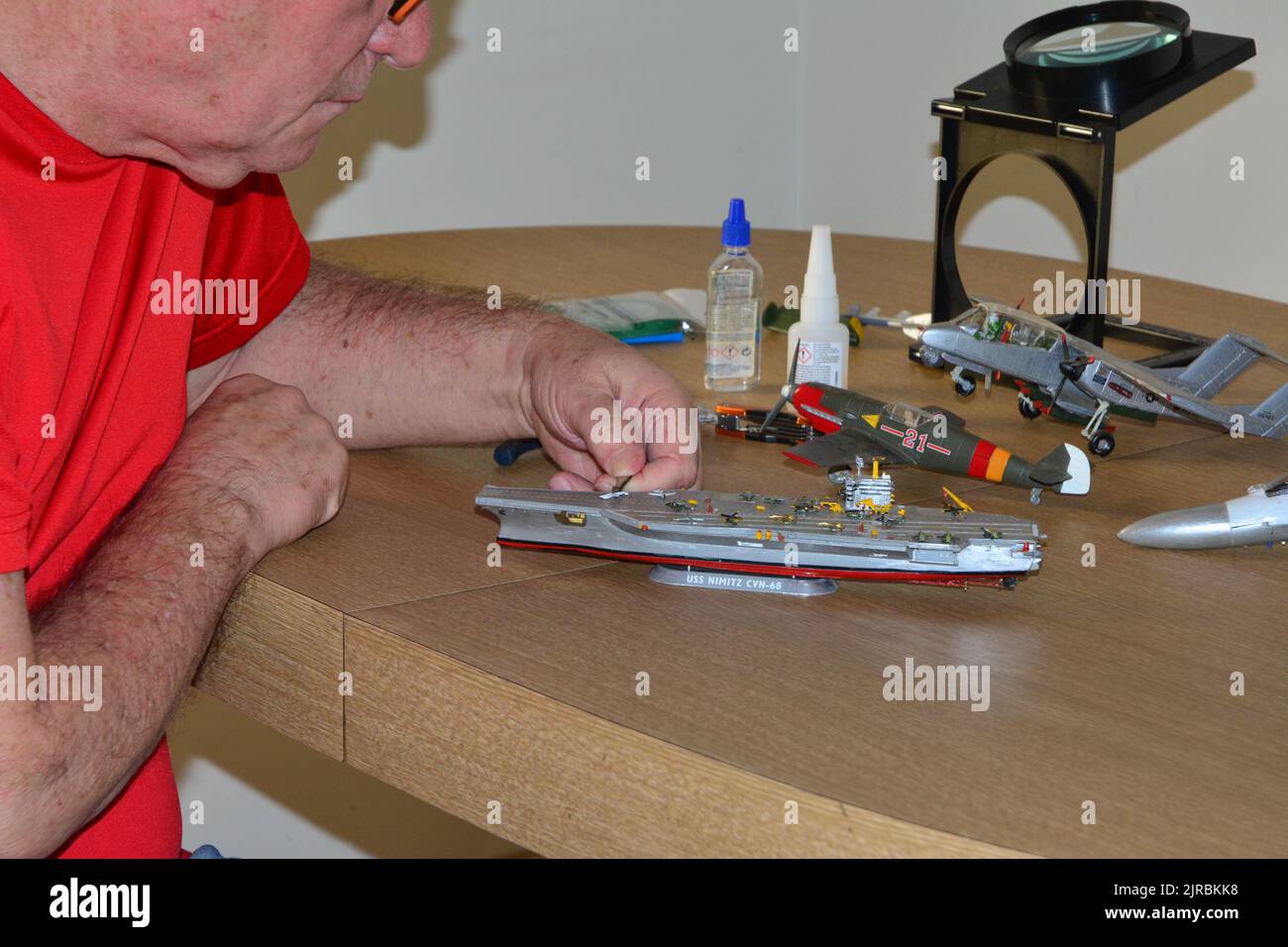 plastic model kit, man with glasses using tweezers in plastic model kit using pliers for