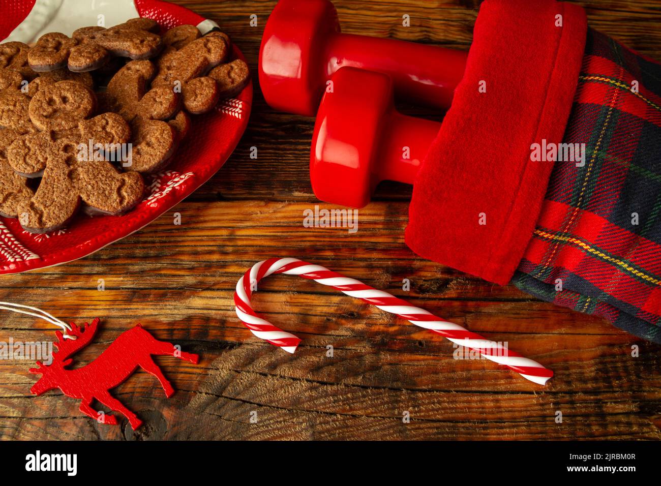Dumbbells in a stocking. Exercise equipment as Christmas gift idea. Gym fitness holiday season composition, with gingerbread man cookies and ornaments. Stock Photo