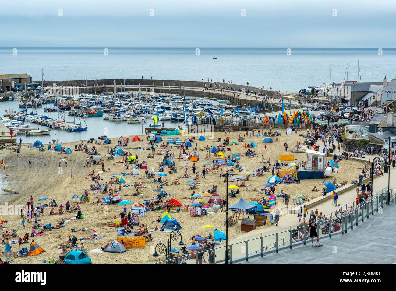 Lyme Regis, Dorset, UK. 23rd Aug, 2022. UK Weather: Holidaymakers make the best of the bright sunny spells on a warm, sunny and somewhat muggy day at the busy seaside resort of Lyme Regis. The weather is set to improve, becoming increasingly bright and sunny as we head towards the August bank holiday weekend. Credit: Celia McMahon/Alamy Live News Stock Photo