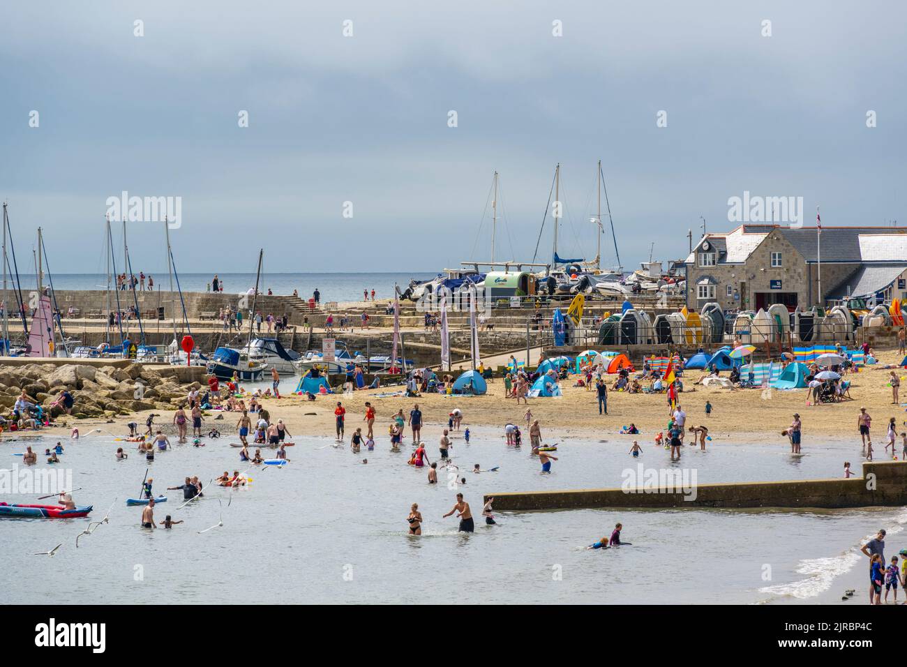 Lyme Regis, Dorset, UK. 23rd Aug, 2022. UK Weather: Holidaymakers make the best of the bright sunny spells on a warm, sunny and somewhat muggy day at the busy seaside resort of Lyme Regis. The weather is set to improve, becoming increasingly bright and sunny as we head towards the August bank holiday weekend. Credit: Celia McMahon/Alamy Live News Stock Photo