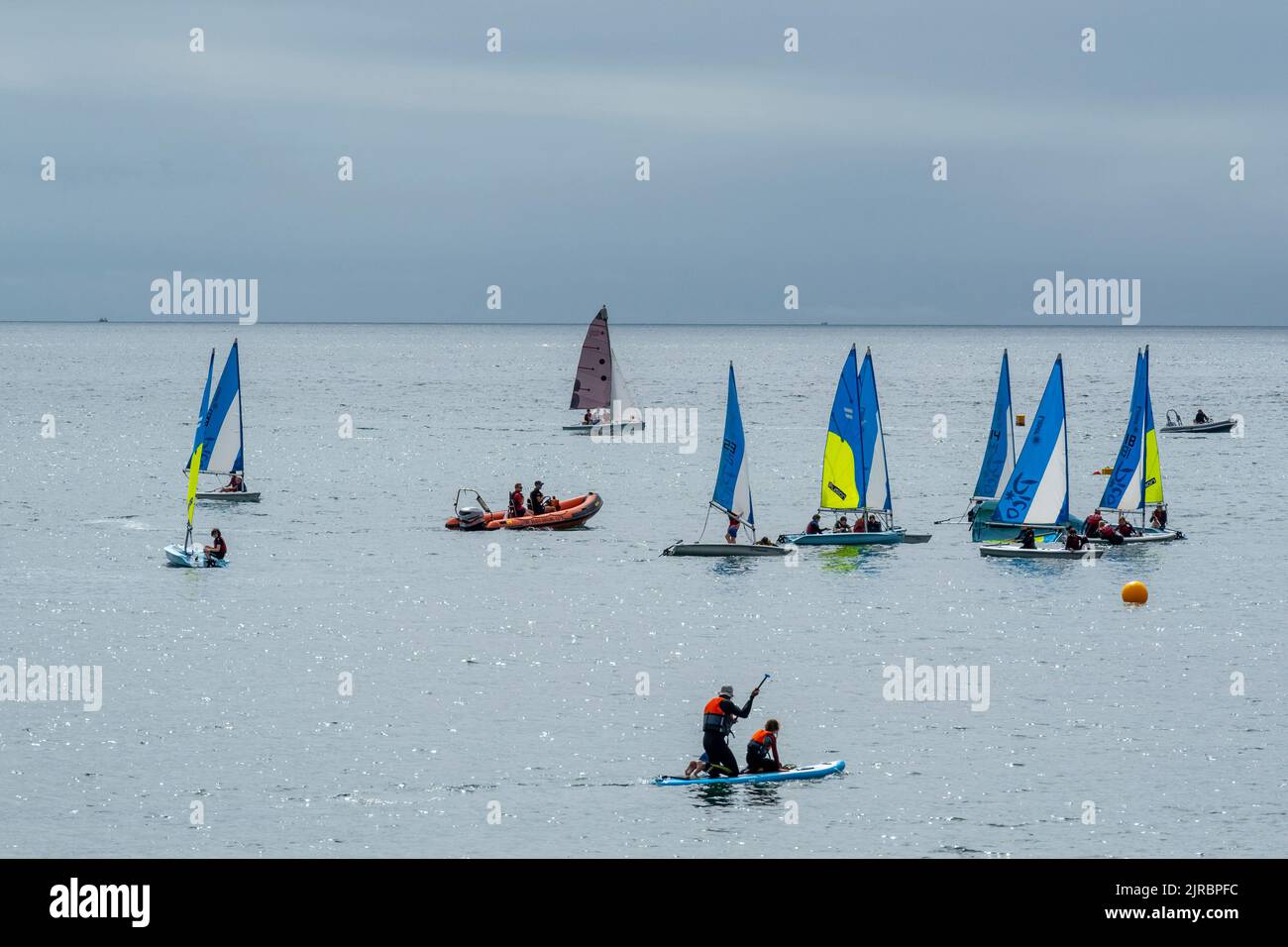 Lyme Regis, Dorset, UK. 23rd Aug, 2022. UK Weather: Brightly coloured sailing boats in the sea at Lyme Regis on a warm and muggy day. The weather is set to improve, becoming increasingly bright and sunny as we head towards the August bank holiday weekend. Credit: Celia McMahon/Alamy Live News Stock Photo