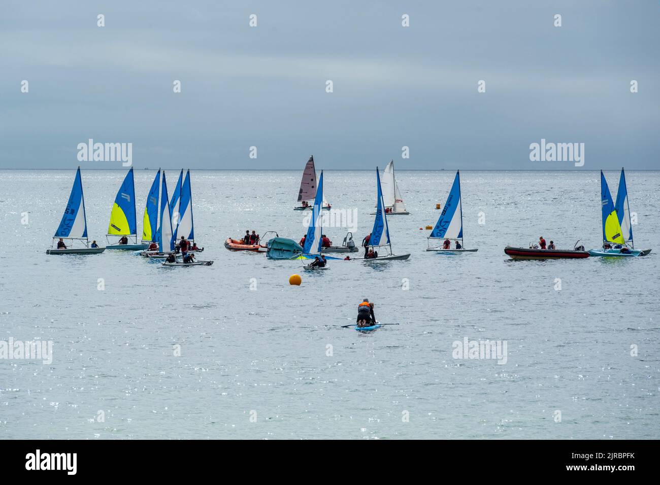 Lyme Regis, Dorset, UK. 23rd Aug, 2022. UK Weather: Brightly coloured sailing boats in the sea at Lyme Regis on a warm and muggy day. The weather is set to improve, becoming increasingly bright and sunny as we head towards the August bank holiday weekend. Credit: Celia McMahon/Alamy Live News Stock Photo