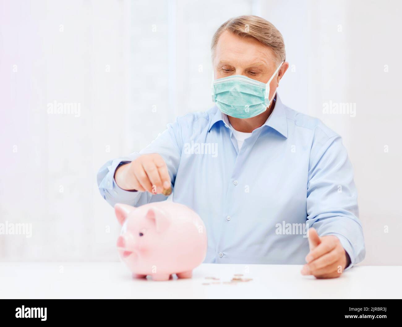 old man in mask putting coin into big piggy bank Stock Photo - Alamy